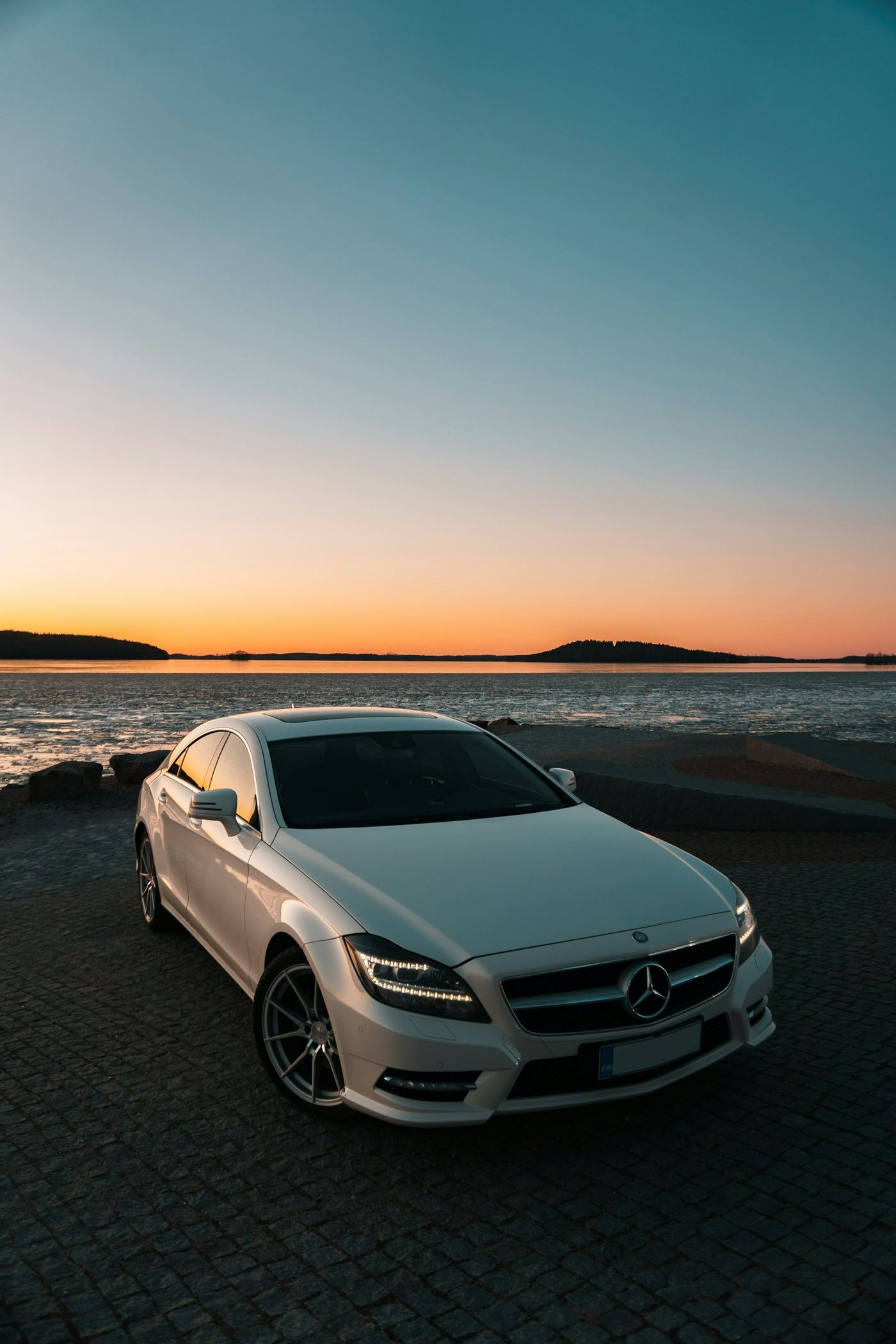 A silver Mercedes sedan at sunset