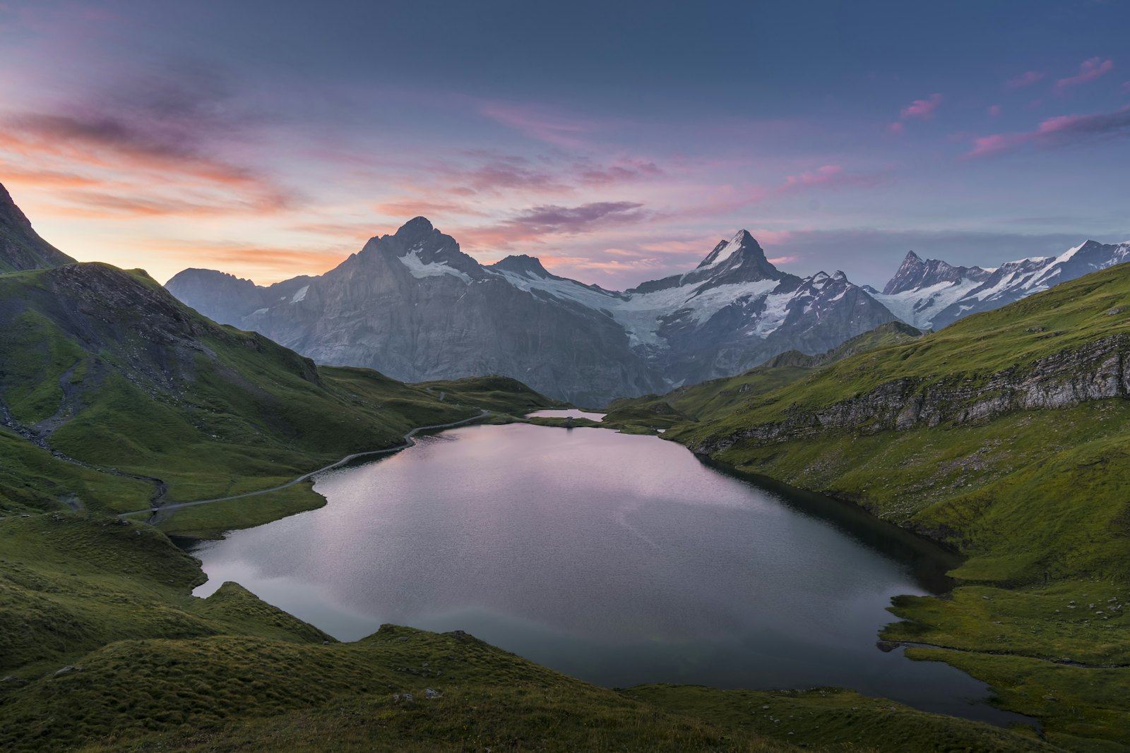 A still mountain lake at dusk below snow-capped peaks