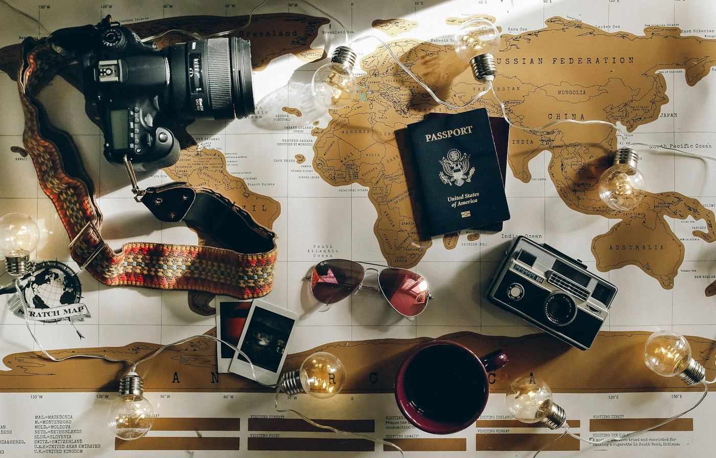 A travel flat-lay: passport, camera and a world map